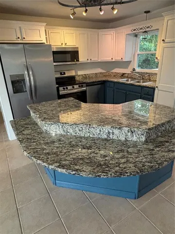 a kitchen with stainless steel appliances granite countertop a refrigerator and a stove top oven