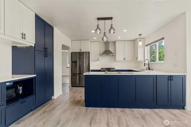 a kitchen with stainless steel appliances granite countertop a stove a sink dishwasher a refrigerator and a wooden cabinets