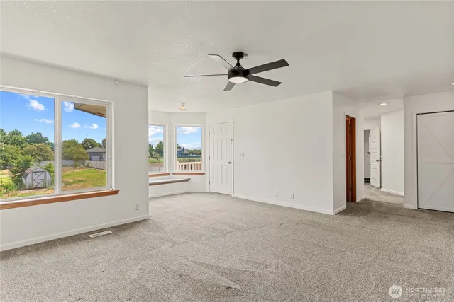 a view of an empty room with a window and a ceiling fan