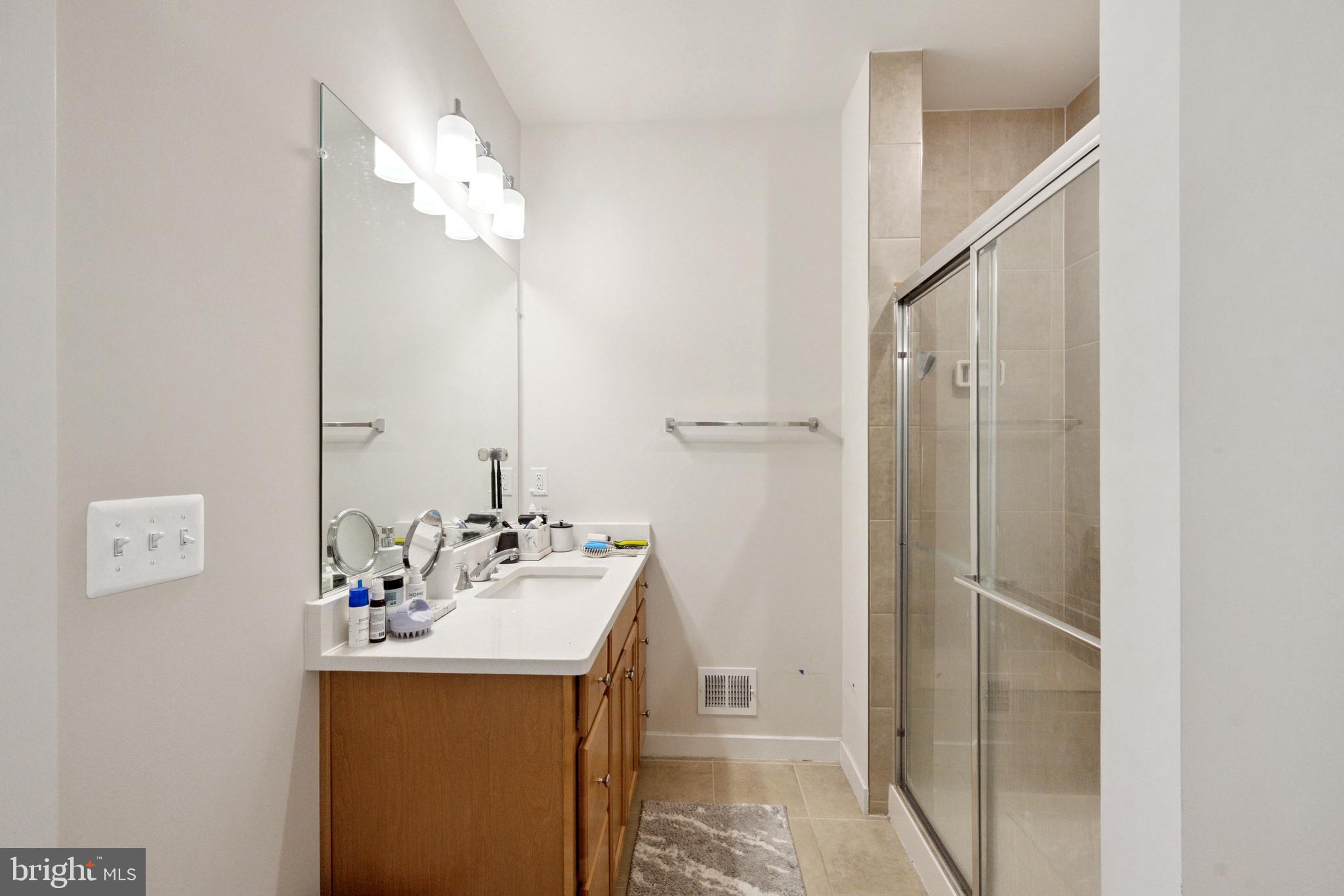 13506 Innovation Station Loop, Unit 2B Herndon, VA 20171 - Photo 28 of 32 a bathroom with a sink a mirror and a shower