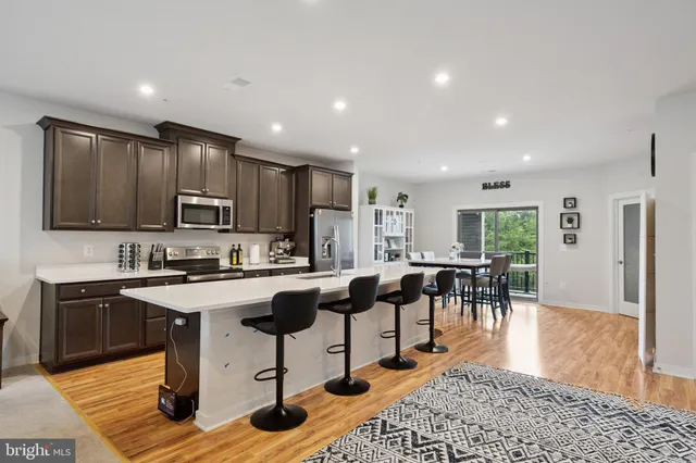 a living room with stainless steel appliances kitchen island granite countertop furniture a rug a kitchen island a stove a refrigerator and a sink