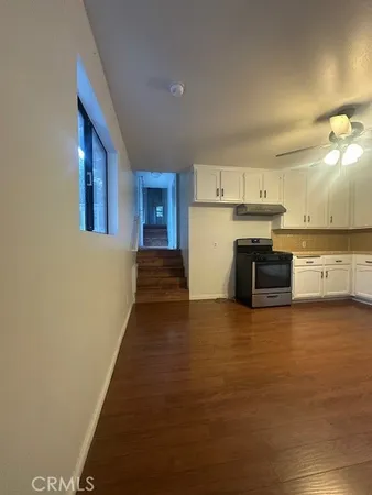 a view of a kitchen with a sink and dishwasher a stove top oven with wooden floor