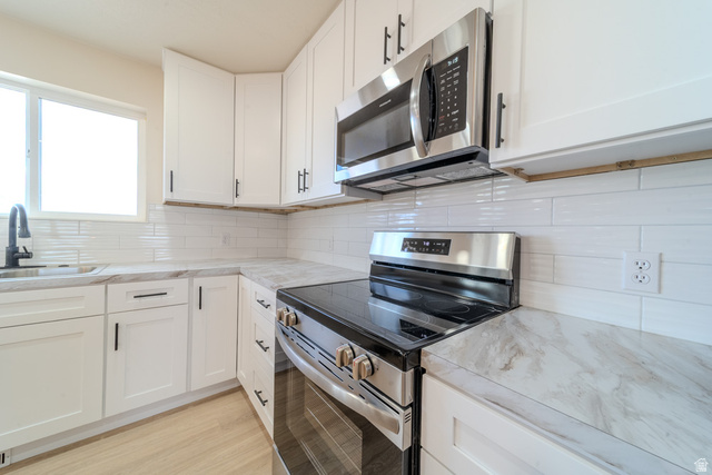 130 Pole Line Road, Unit 2 Roosevelt, UT 84066 - Photo 12 of 33 Kitchen featuring white shaker-style cabinetry, stainless steel appliances, a subway tile backsplash, and light-toned countertops