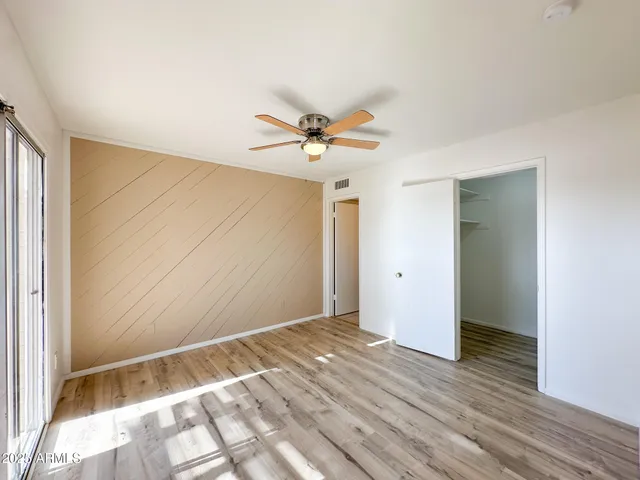 a view of a room with wooden floor and a ceiling fan