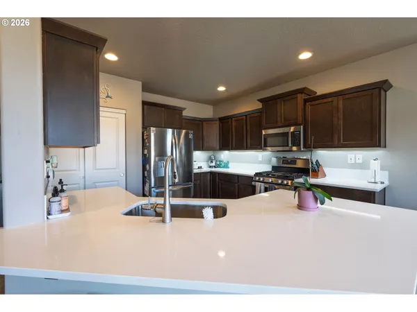a kitchen with stainless steel appliances kitchen island granite countertop a sink refrigerator and cabinets