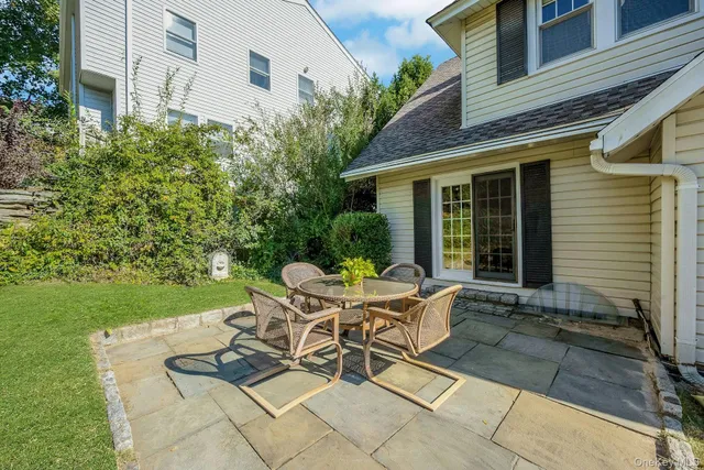 a backyard of a house with table and chairs plants and large tree