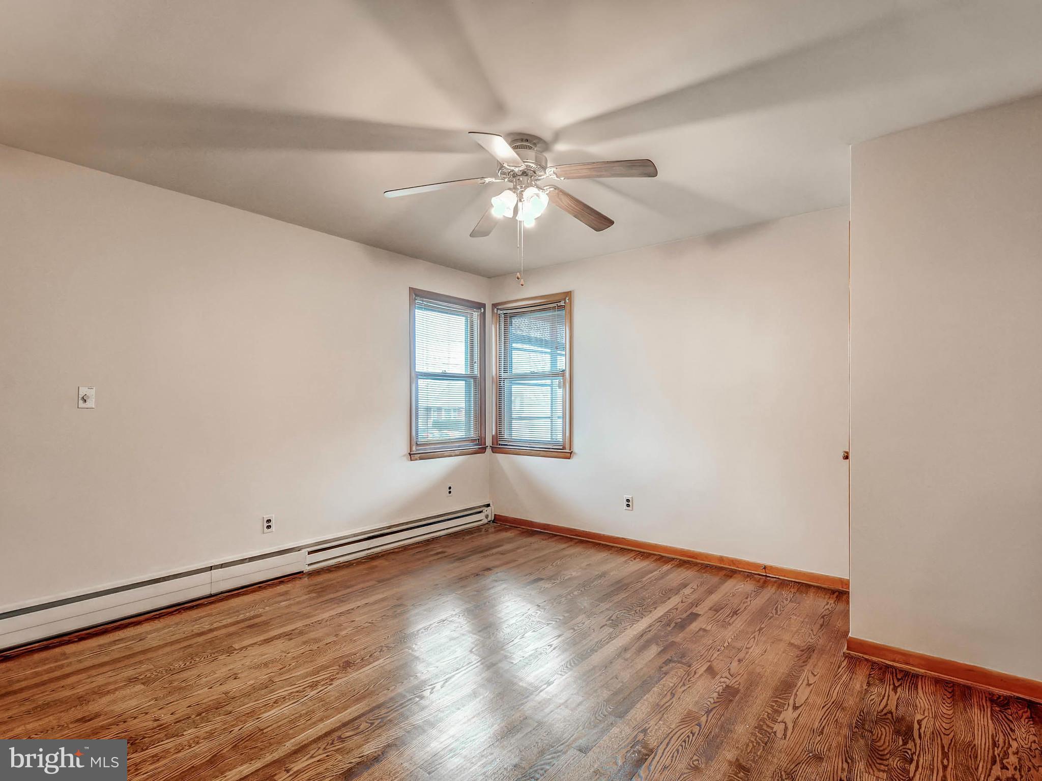 7306 Manchester Road Baltimore, MD 21222 - Photo 12 of 24 an empty room with wooden floor chandelier fan and windows