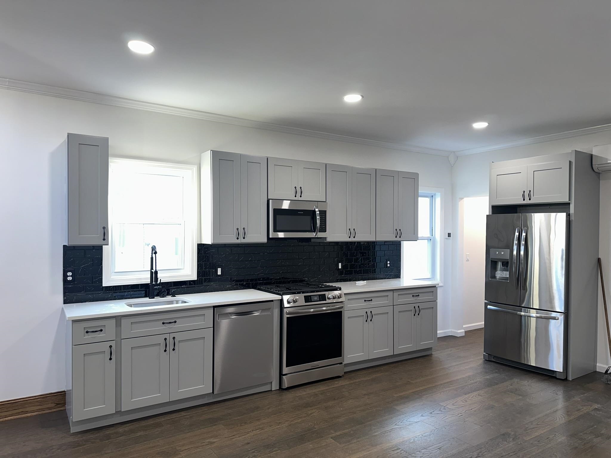 a kitchen with stainless steel appliances granite countertop a refrigerator a sink a stove a microwave and wooden cabinets