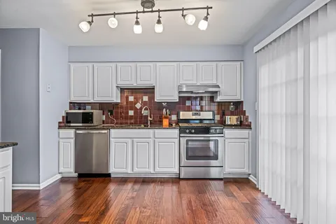 a kitchen with cabinets wooden floor and stainless steel appliances
