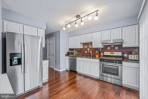 a kitchen with stainless steel appliances and wooden floor