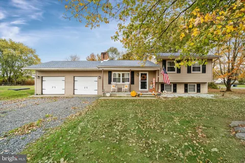 a front view of a house with a garden and trees