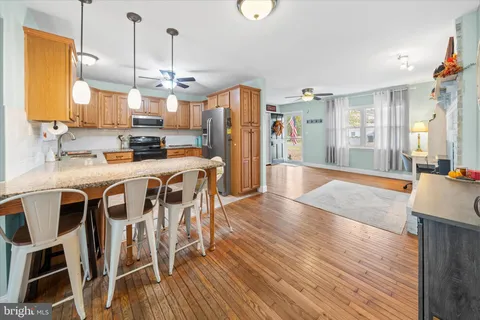 a kitchen with stainless steel appliances a dining table chairs stove and wooden floor