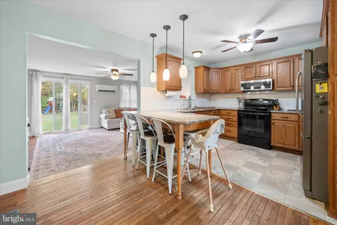 a kitchen with stainless steel appliances a dining table chairs stove and a wooden floor