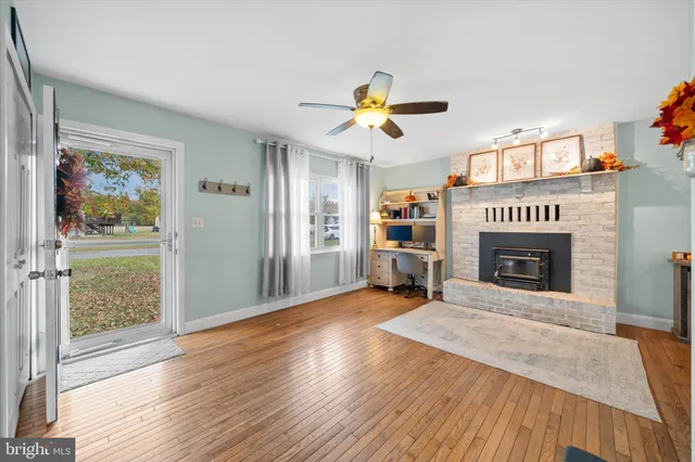 a view of a livingroom with a fireplace a ceiling fan and window