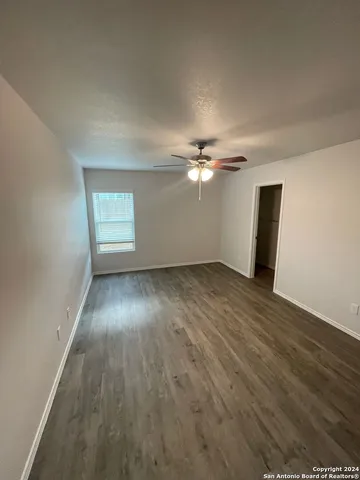 an empty room with wooden floor fan and windows