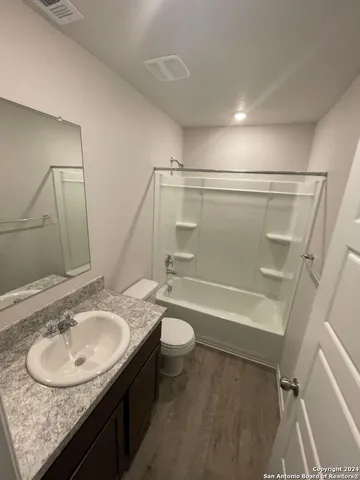 a bathroom with a granite countertop sink toilet and a mirror