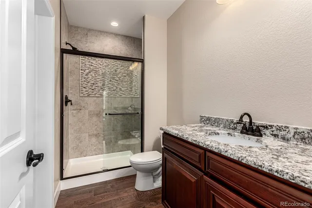 a bathroom with a granite countertop toilet and a sink