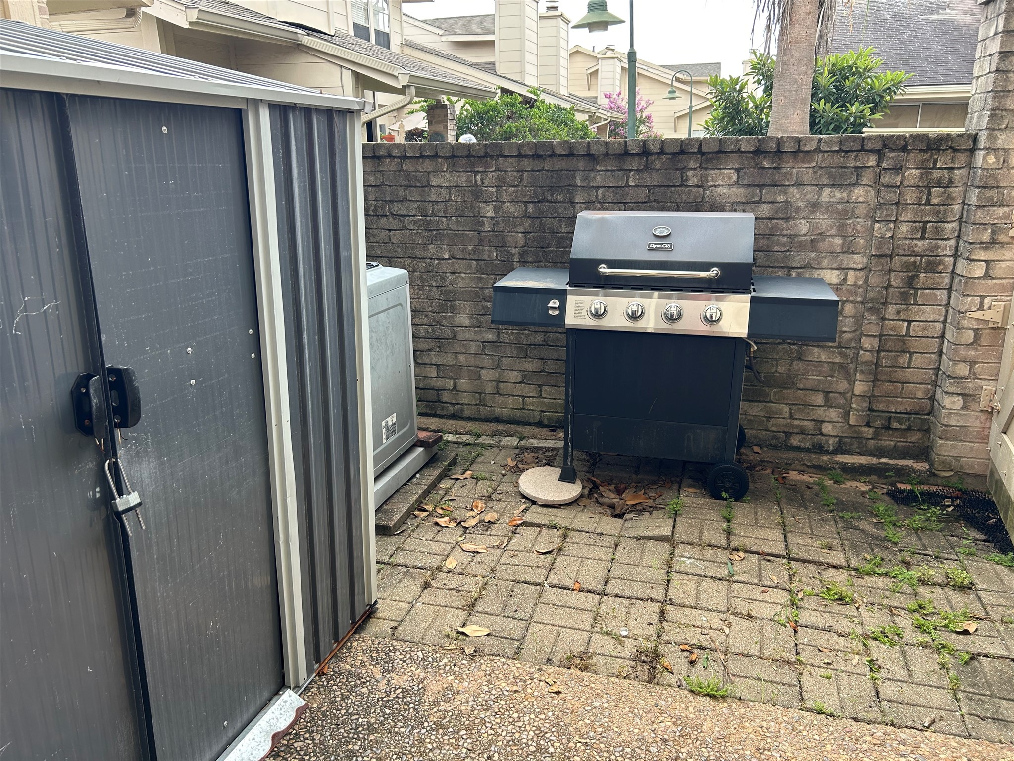 13034 Leader Street, Unit 965 Houston, TX 77072 - Photo 29 of 32 This outdoor space features a compact patio area with a brick wall, equipped with a barbecue grill and a storage shed. Ideal for small gatherings or personal relaxation.