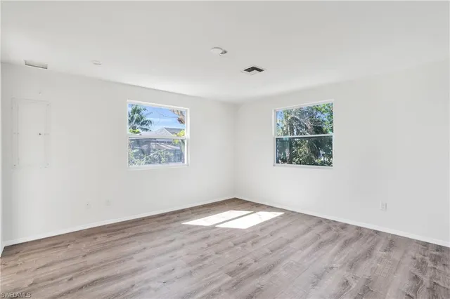an empty room with wooden floor and windows