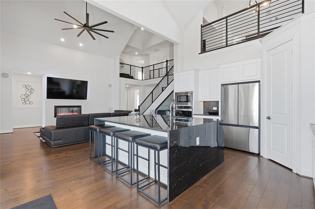 7548 Ridge Lane Grand Prairie, TX 75054 - Photo 12 of 35 Kitchen with a ceiling fan, stainless steel appliances, dark stone countertops, dark wood-style floors, and a high ceiling