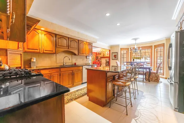 a kitchen with stainless steel appliances granite countertop a stove top oven a dining table and chairs with wooden floor