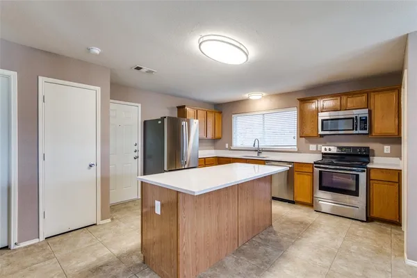 a room with stainless steel appliances kitchen island granite countertop a refrigerator and a stove top oven