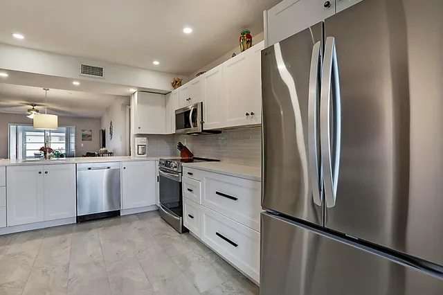 a kitchen with white cabinets and stainless steel appliances