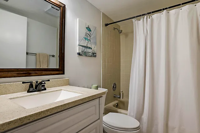 a bathroom with a granite countertop sink toilet and a mirror