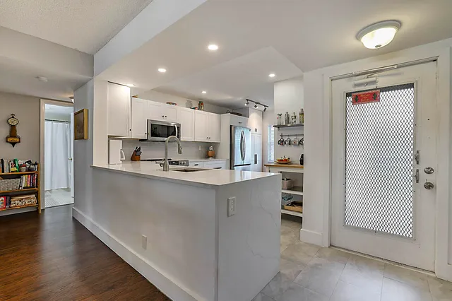a kitchen with stainless steel appliances kitchen island granite countertop a refrigerator and a stove top oven