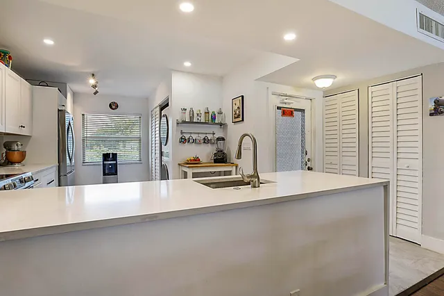 a large kitchen with stainless steel appliances a large counter top a stove and a sink