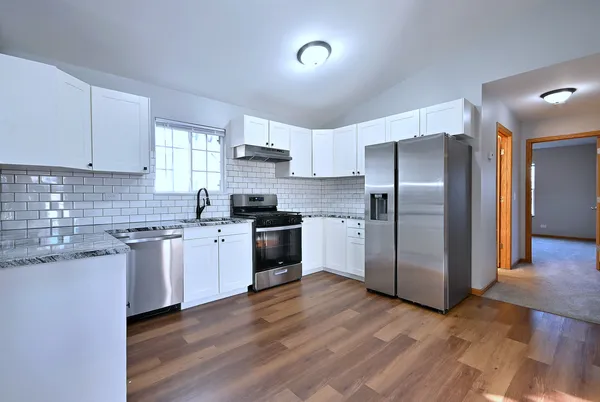 a kitchen with granite countertop a refrigerator and a stove top oven
