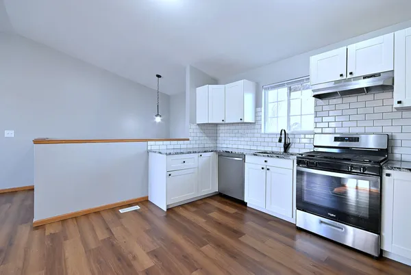 a kitchen with granite countertop wooden floors and white stainless steel appliances
