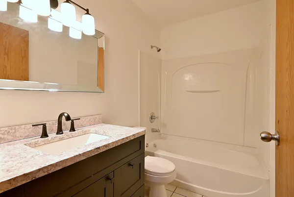 a bathroom with a granite countertop sink a toilet and bathtub