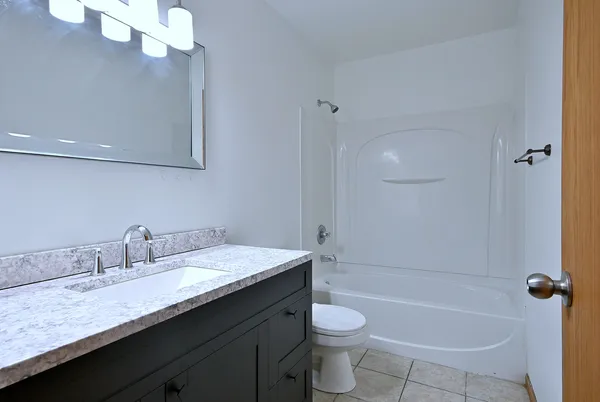 a bathroom with a granite countertop sink a toilet and bathtub