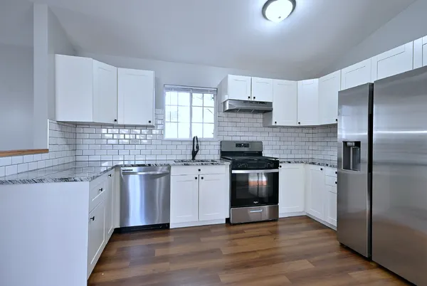 a kitchen with granite countertop a refrigerator stove and sink