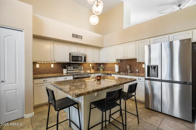 a kitchen with stainless steel appliances granite countertop a refrigerator a stove a sink a table and chairs