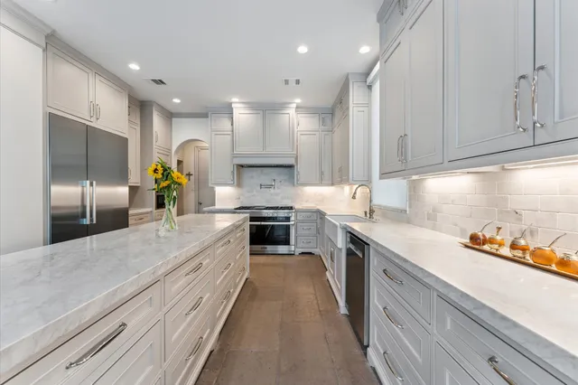 a large kitchen with a large counter top stainless steel appliances and cabinets