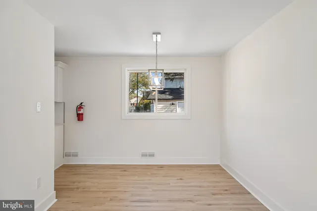 a view of an empty room with wooden floor and window
