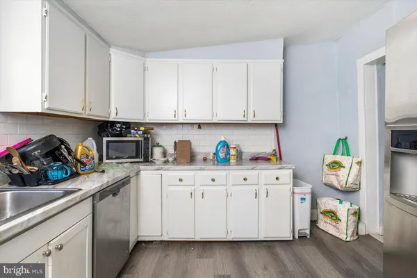 a kitchen with white cabinets and wooden floor
