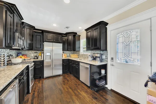 a kitchen with stainless steel appliances granite countertop a refrigerator a sink dishwasher a stove and white countertops with wooden floor