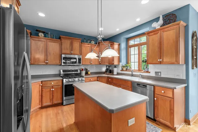 a kitchen with stainless steel appliances granite countertop a refrigerator a sink a stove and a wooden cabinets