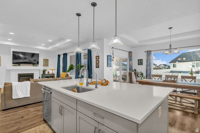 2454 West Jackson Street Mapleton, UT 84664 - Photo 63 of 63 Kitchen with a tray ceiling, a glass covered fireplace, light wood finished floors, open floor plan, and light stone countertops