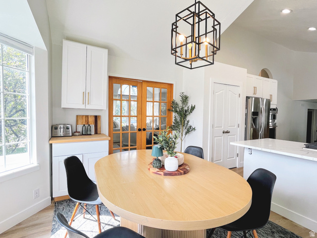 12169 Hidden Valley Road, Unit 44 Sandy, UT 84092 - Photo 14 of 49 Vaulted ceiling, white cabinetry with gold-tone hardware, wood-finish flooring, French doors, and a kitchen island with a light-tone countertop