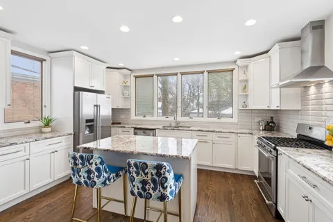a kitchen with granite countertop kitchen island stainless steel appliances a sink stove and cabinets