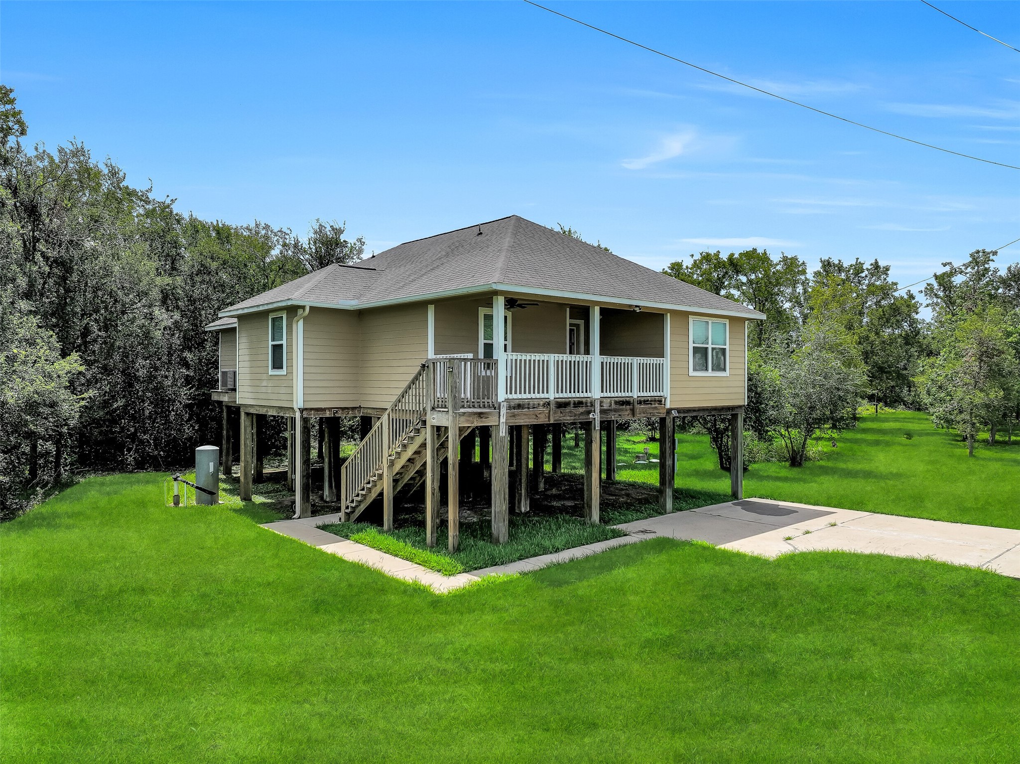 11930 Bastrop Beach Road Angleton, TX 77515 - Photo 6 of 29 Built on sturdy 10-foot pillars, this elevated custom home provides covered parking and storage below while offering added peace of mind. Surrounded by mature trees and open green space, the more-than-acre homesite delivers privacy in every direction.