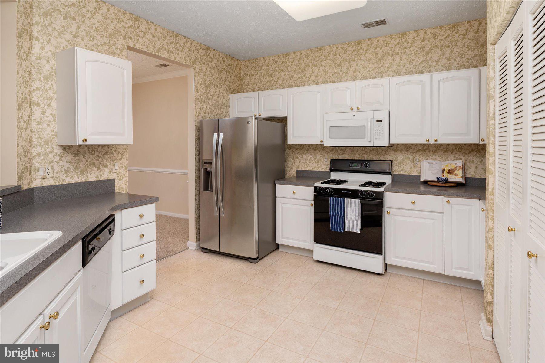 2502 Amber Orchard Court West, Unit 104 Odenton, MD 21113 - Photo 11 of 28 a kitchen with white cabinets and stainless steel appliances