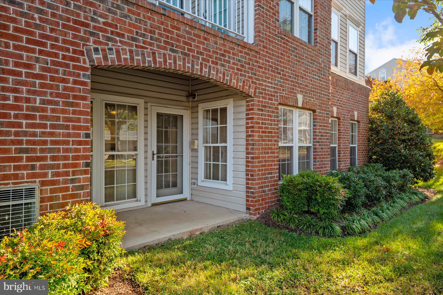 2502 Amber Orchard Court West, Unit 104 Odenton, MD 21113 - Photo 18 of 28 a view of a brick house with a large windows and flower plants