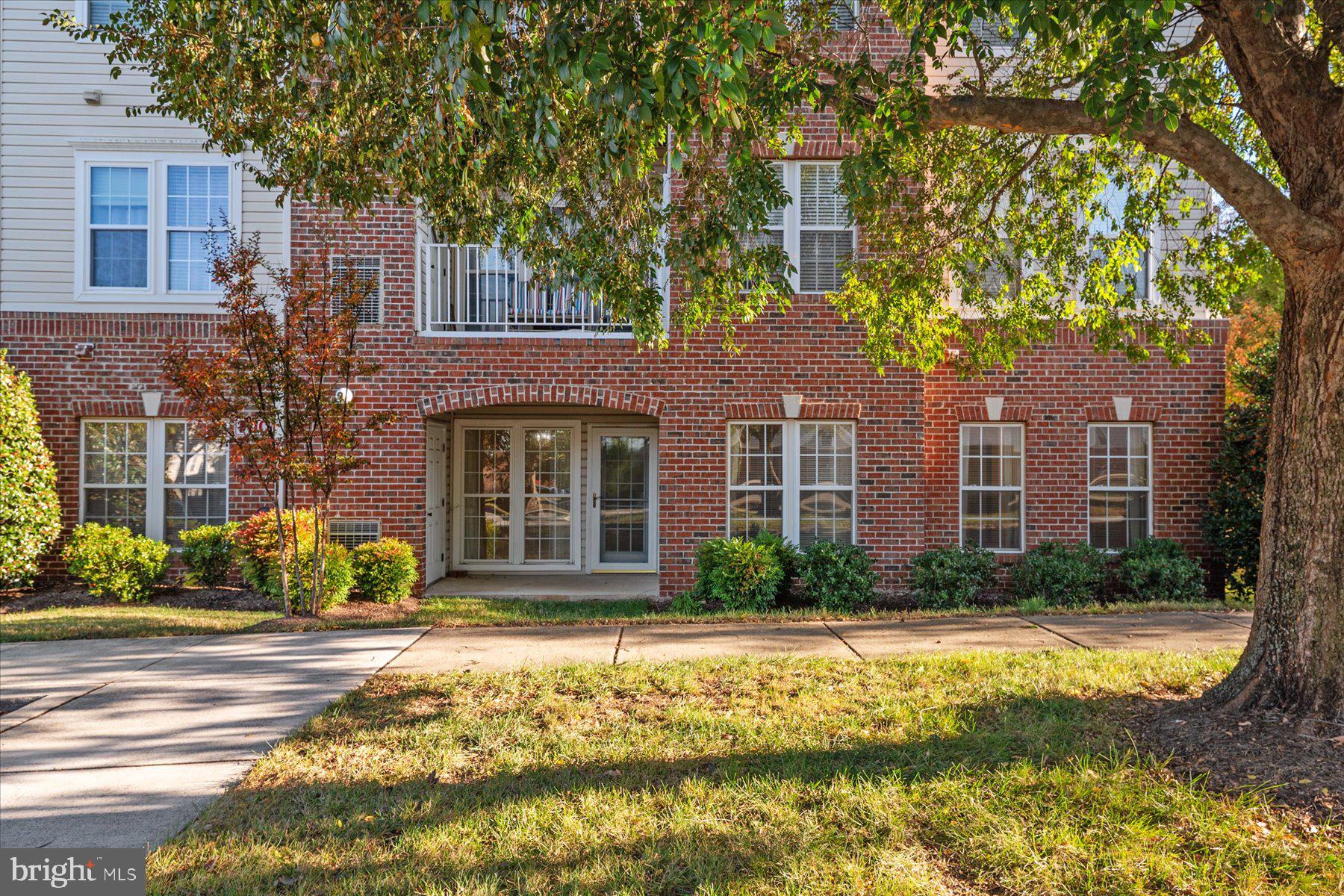 2502 Amber Orchard Court West, Unit 104 Odenton, MD 21113 - Photo 19 of 28 a front view of a house with a yard table and chairs