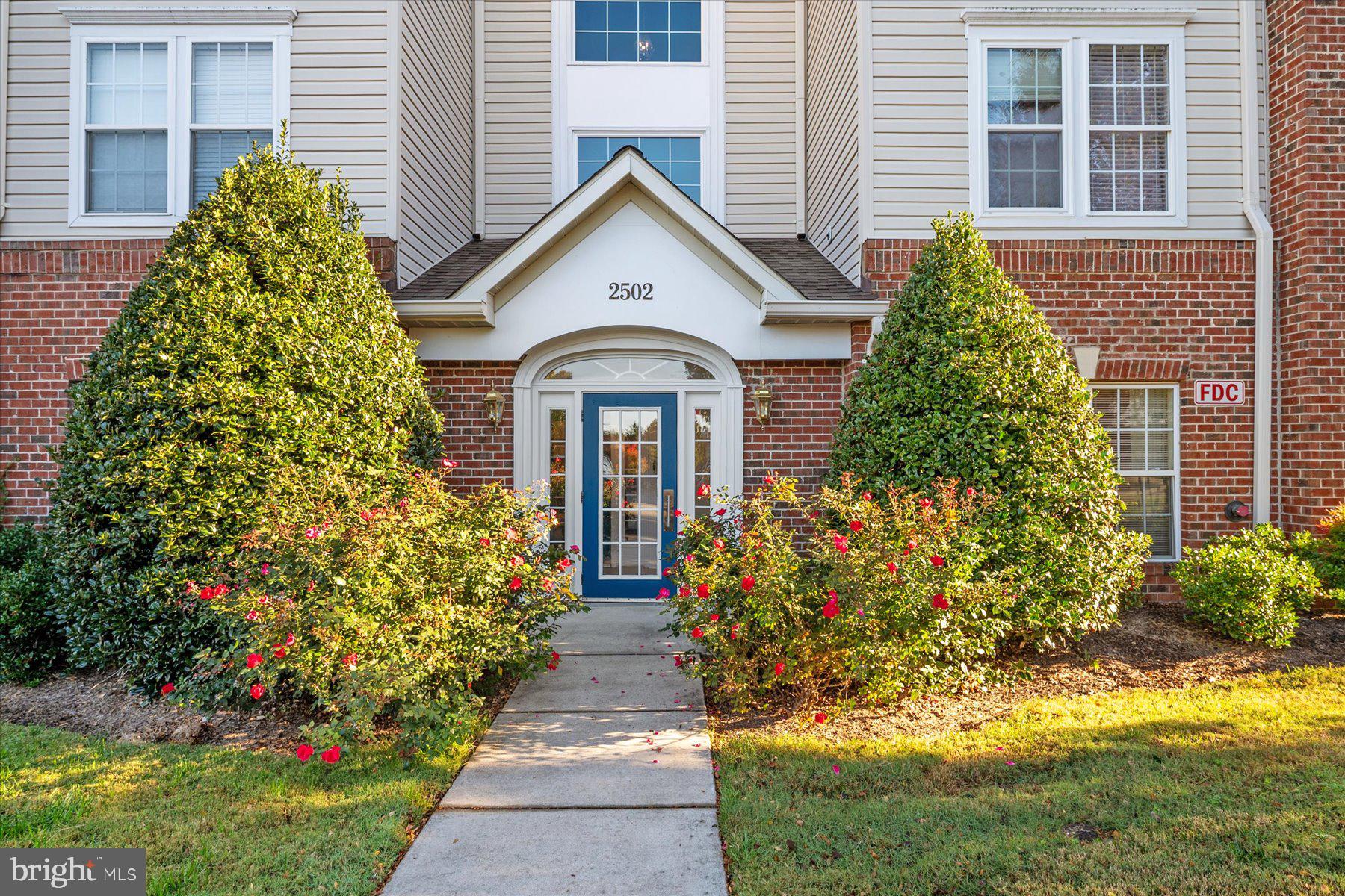 2502 Amber Orchard Court West, Unit 104 Odenton, MD 21113 - Photo 2 of 28 a front view of a house with a garden