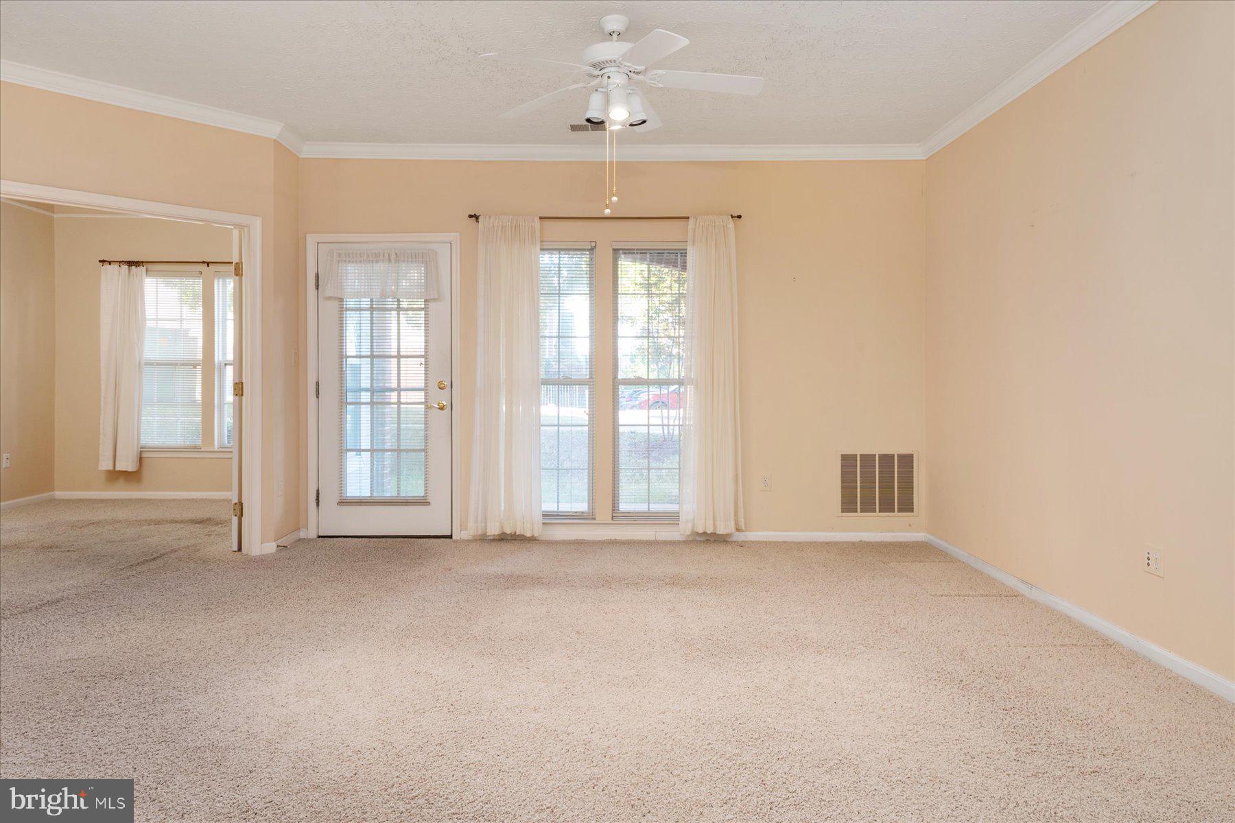 2502 Amber Orchard Court West, Unit 104 Odenton, MD 21113 - Photo 4 of 28 an empty room with windows and chandelier fan